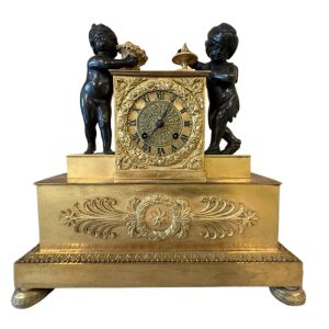 Pendule en bronze doré avec des enfants jouants en patine brune d’époque restauration